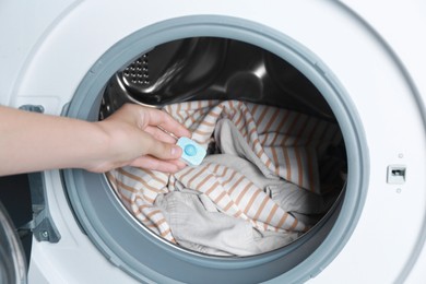 Photo of Woman putting water softener tablet into washing machine, closeup