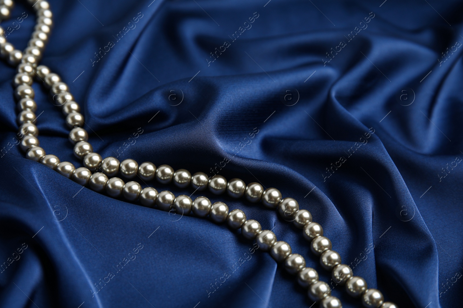 Photo of Beautiful pearls on delicate dark blue silk