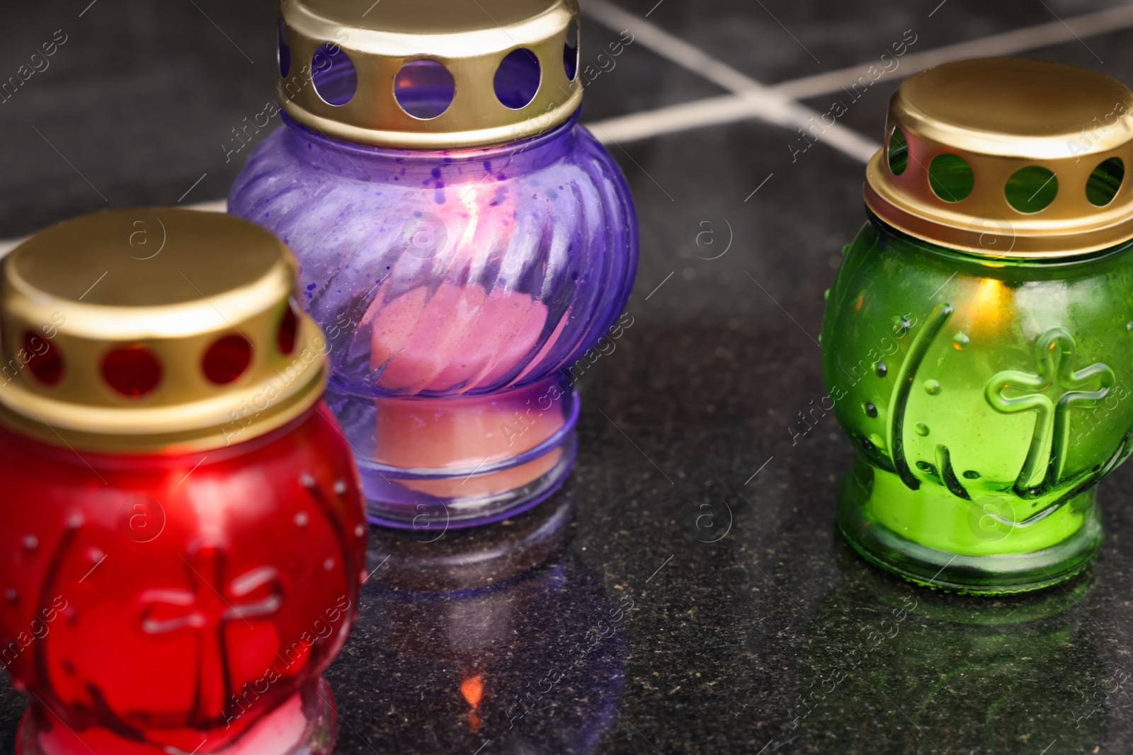 Photo of Different grave lanterns on granite surface at cemetery closeup