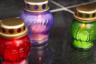 Photo of Different grave lanterns on granite surface at cemetery closeup