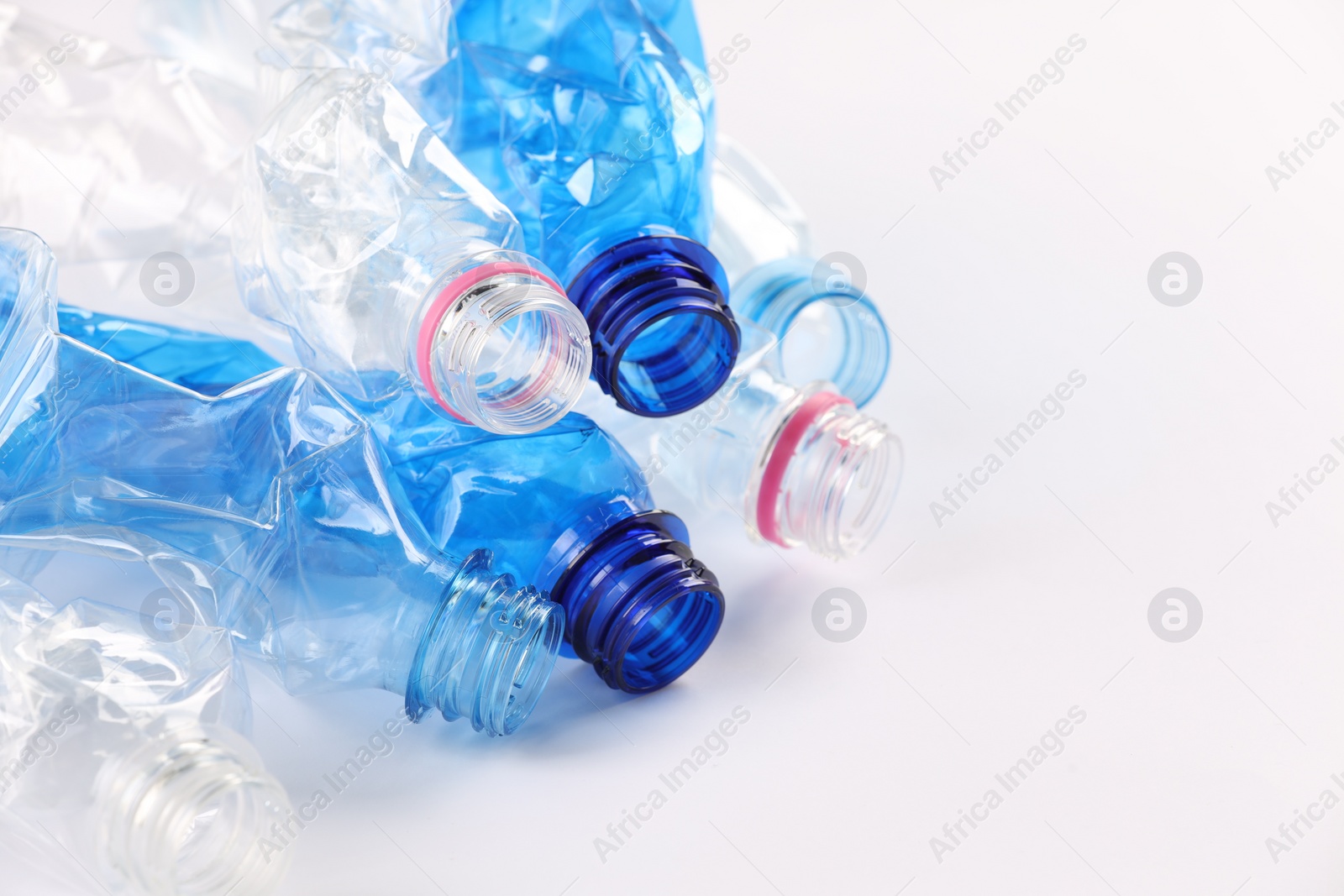 Photo of Crumpled disposable plastic bottles on white background, space for text