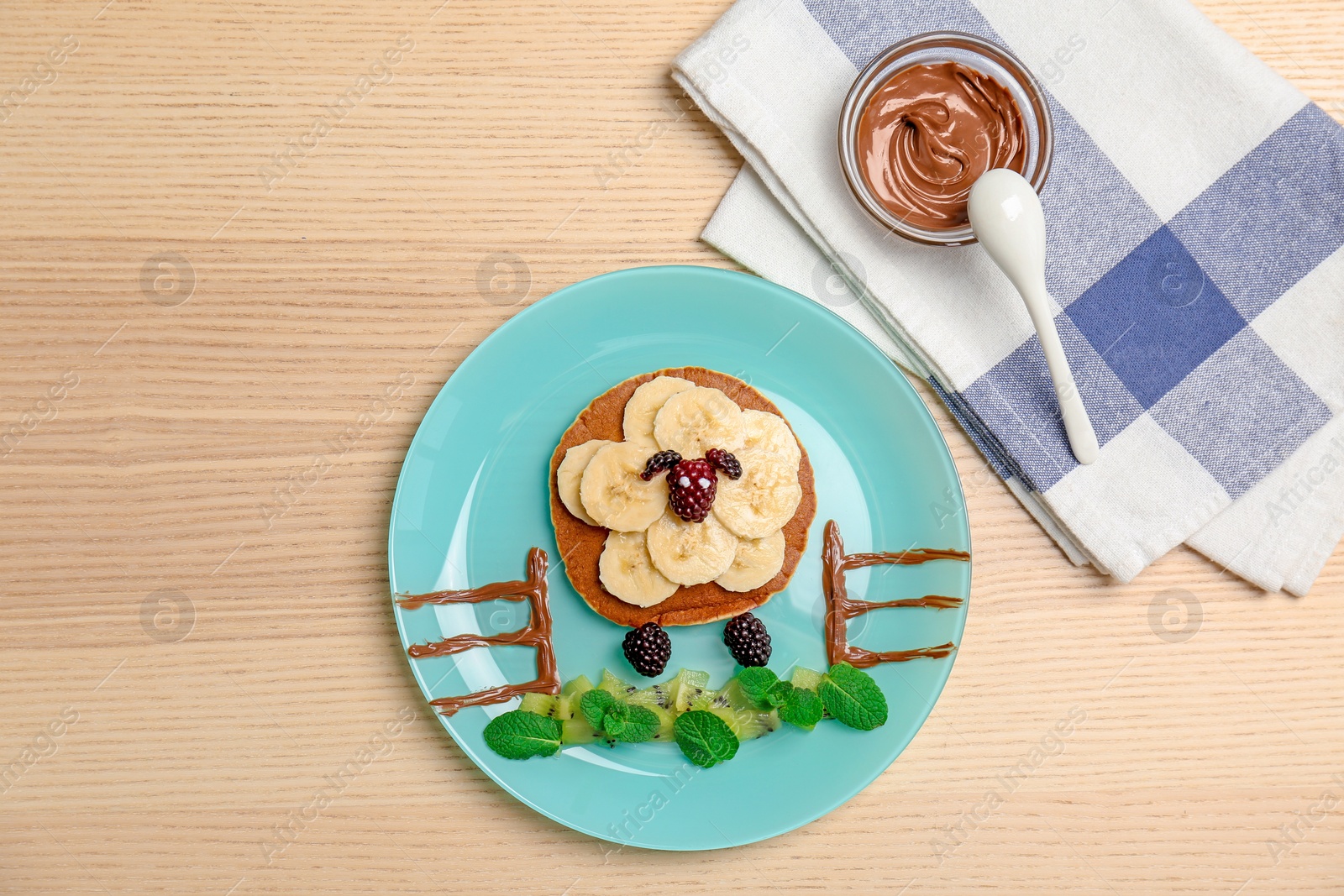 Photo of Funny pancake for kids breakfast on wooden table, top view