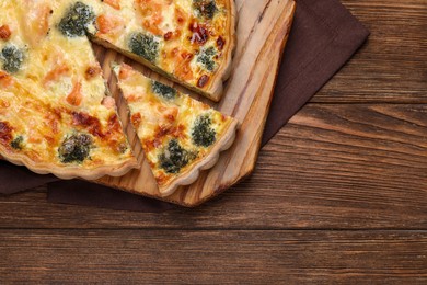 Photo of Delicious homemade quiche with salmon and broccoli on wooden table, top view. Space for text