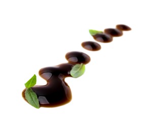 Photo of Balsamic glaze and basil leaves on white background