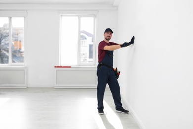 Photo of Handyman in uniform working with screwdriver indoors, space for text. Professional construction tools