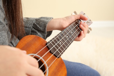 Photo of Little girl playing wooden guitar indoors, closeup