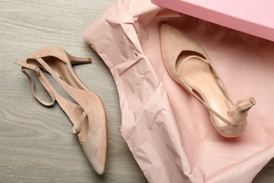 Photo of Pair of beautiful shoes and box on wooden background, flat lay