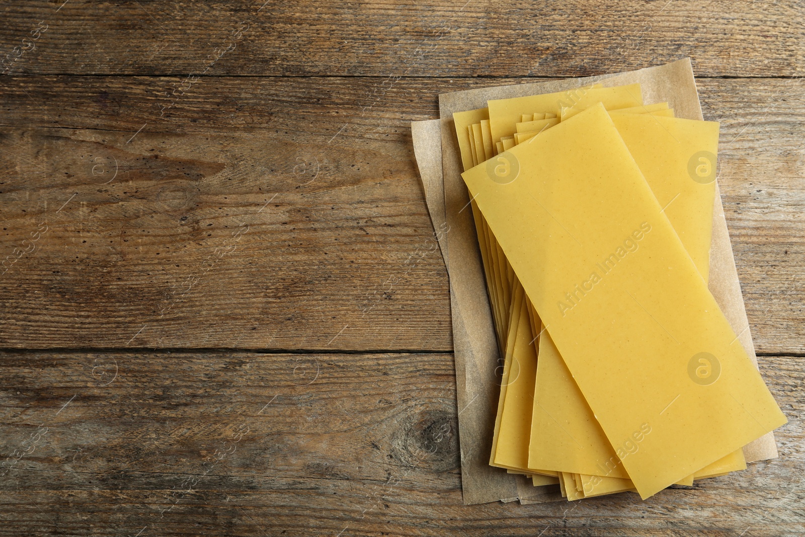 Photo of Uncooked lasagna sheets on wooden background, top view. Space for text