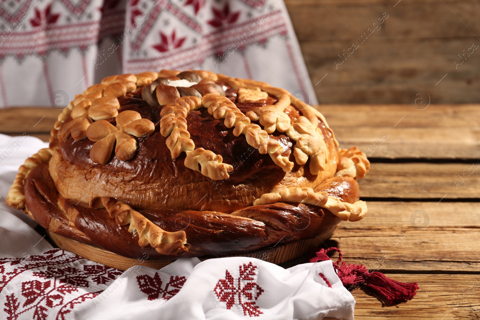 Photo of Korovai with rushnyk on wooden table. Ukrainian bread and salt welcoming tradition