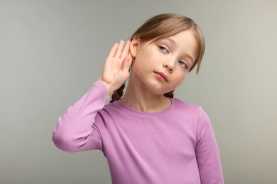 Little girl with hearing problem on grey background