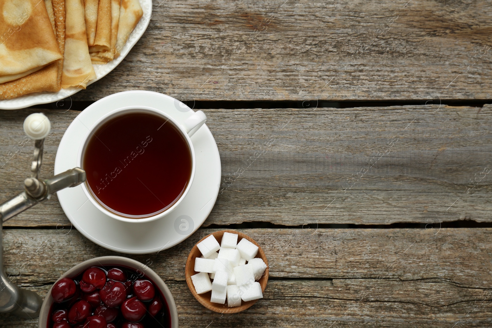 Photo of Metal samovar with cup of tea and treats on wooden table, flat lay. Space for text