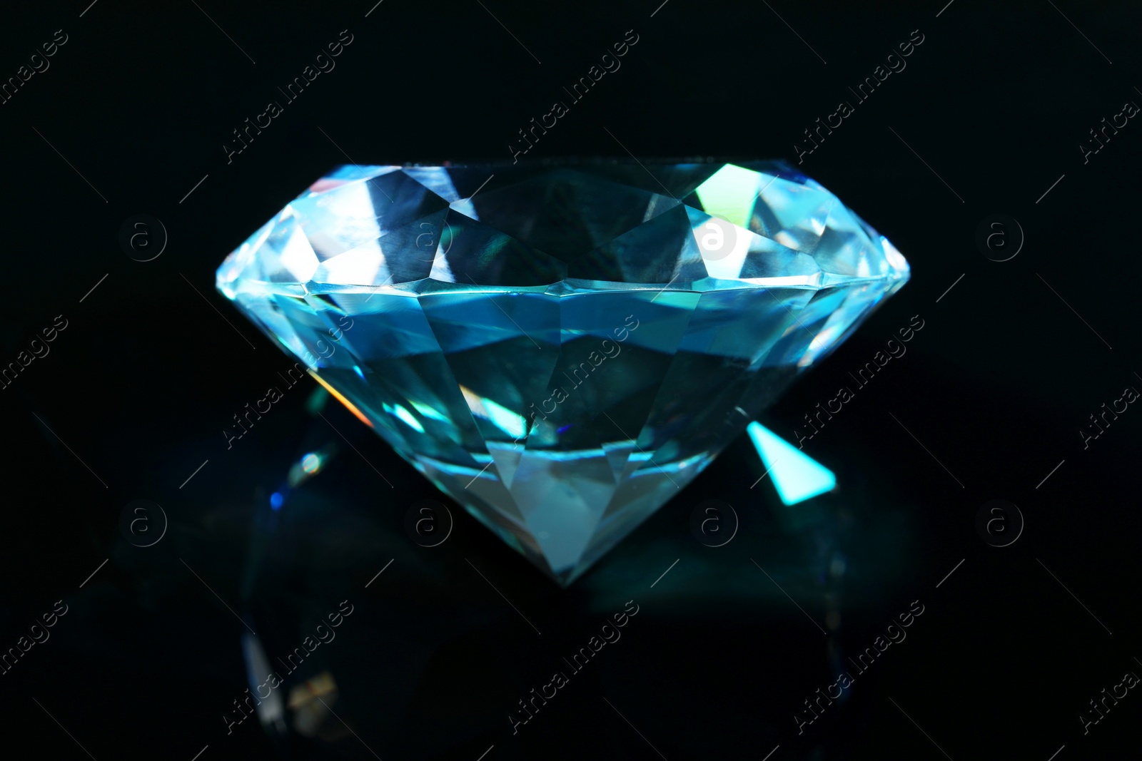 Photo of Beautiful dazzling diamond on black mirror background, closeup