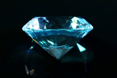 Beautiful dazzling diamond on black mirror background, closeup