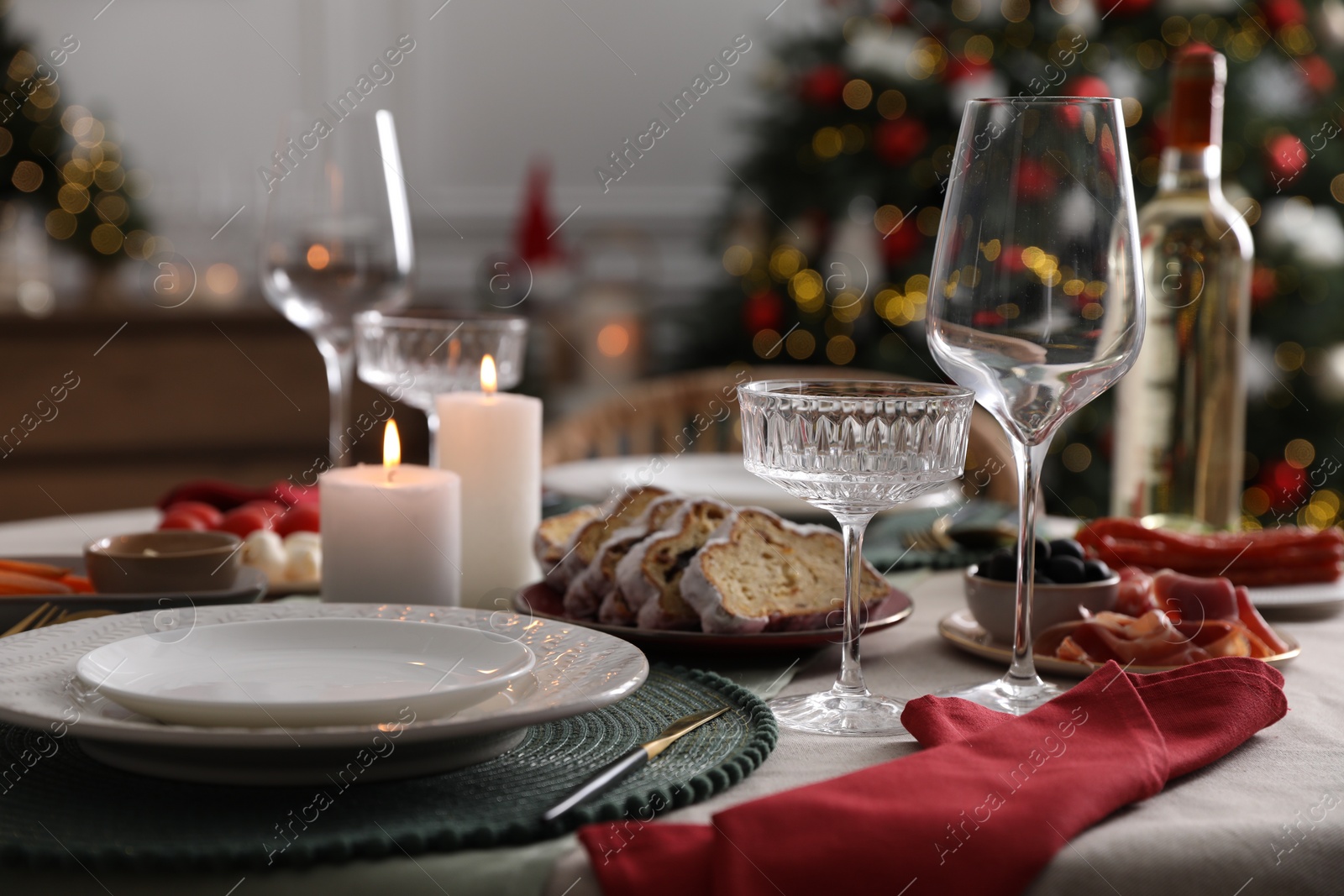 Photo of Christmas table setting with burning candles, appetizers and dishware indoors