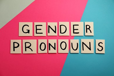 Photo of Paper notes with words Gender Pronouns on color background, flat lay