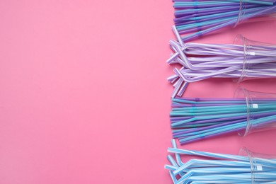 Plastic cups with straws on pink background, flat lay. Space for text