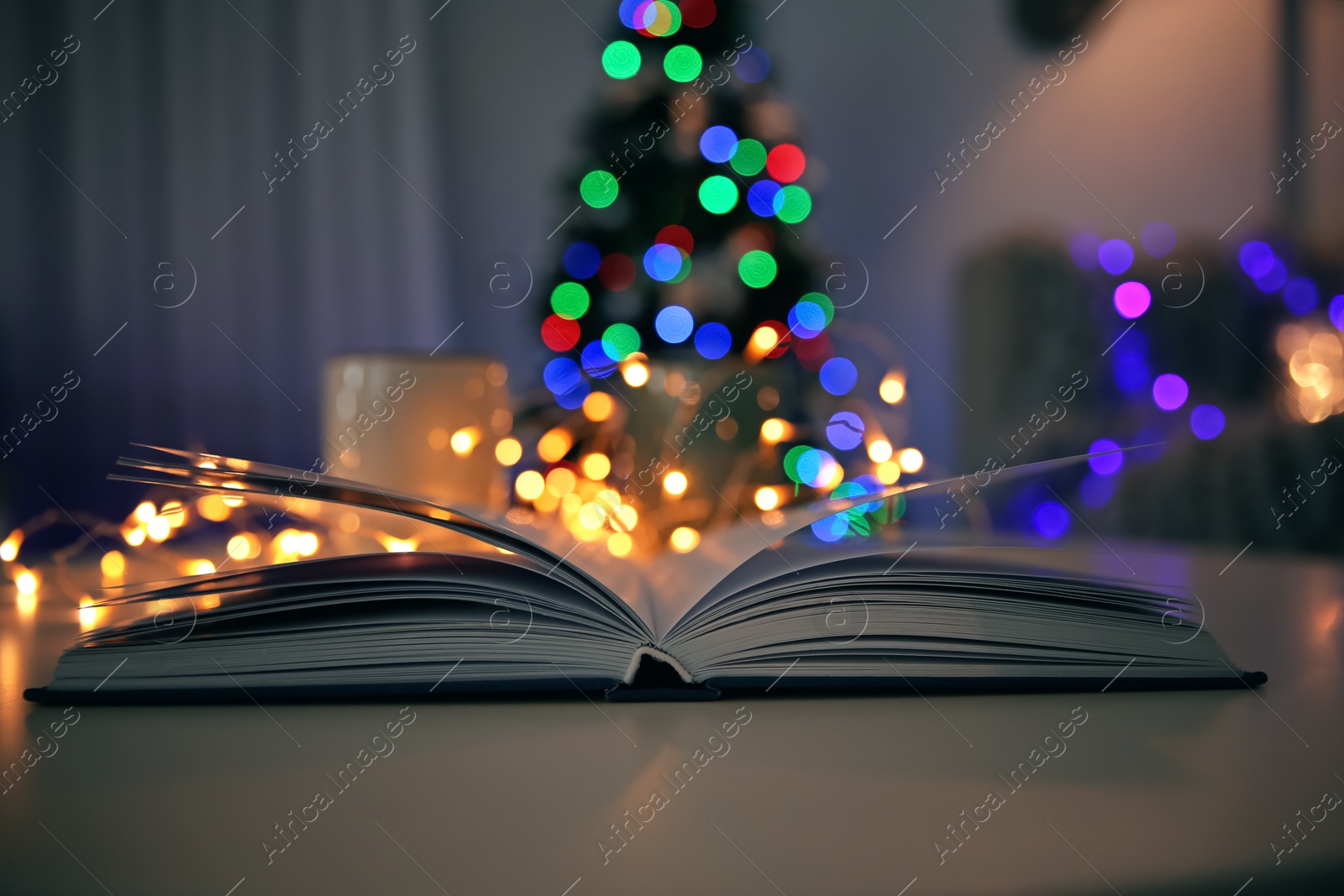 Photo of Open book and blurred Christmas tree on background