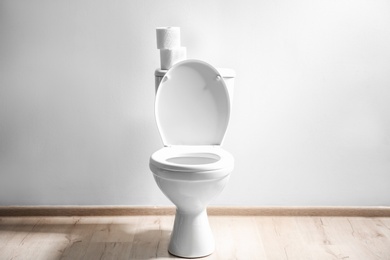 Photo of New ceramic toilet bowl near light wall