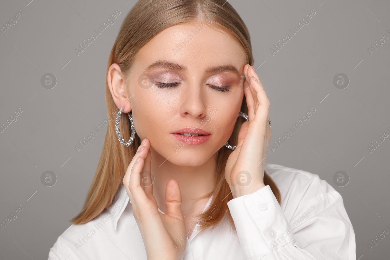 Photo of Beautiful young woman with elegant earrings on gray background