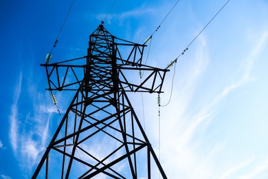 Photo of High voltage tower against beautiful blue sky, low angle view