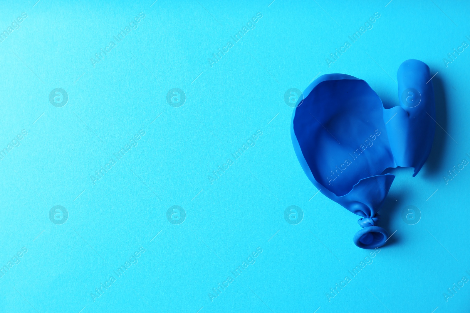 Photo of Popped balloon on color background, top view with space for text