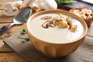 Photo of Delicious cream soup with mushrooms on wooden table, closeup