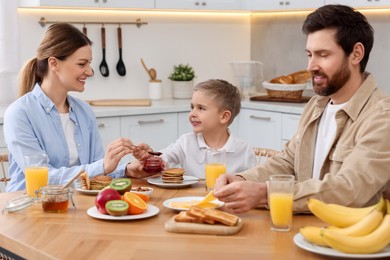 Happy family having breakfast at table in kitchen