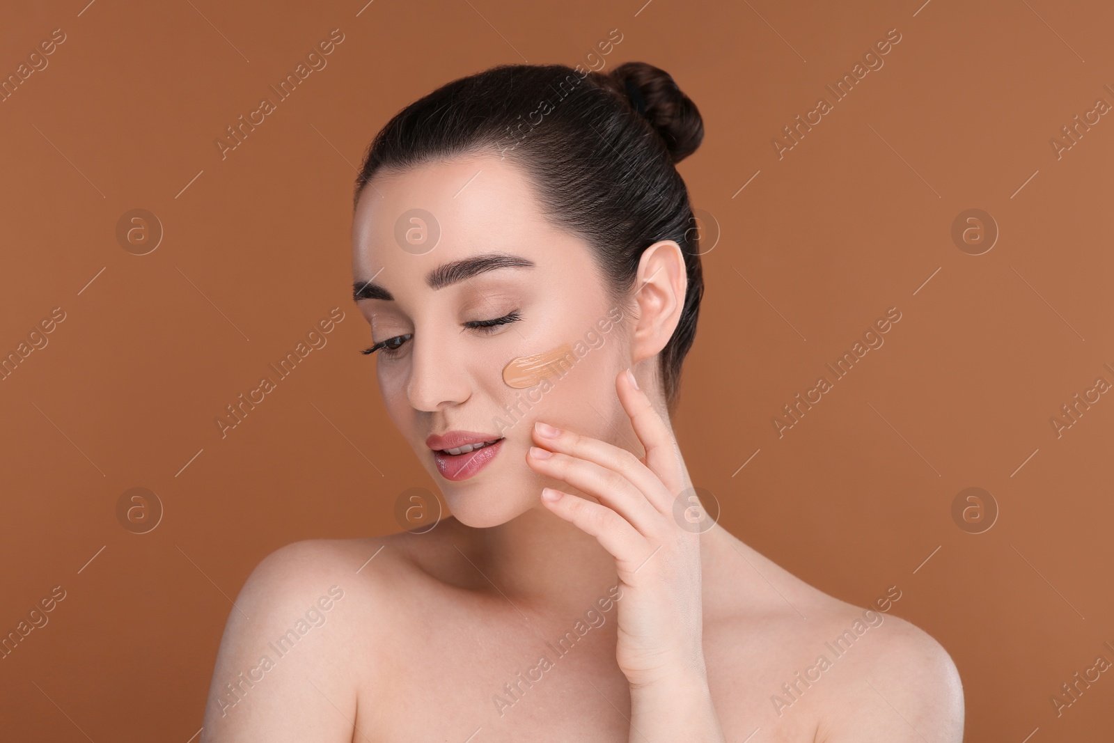 Photo of Woman with swatch of foundation on face against brown background