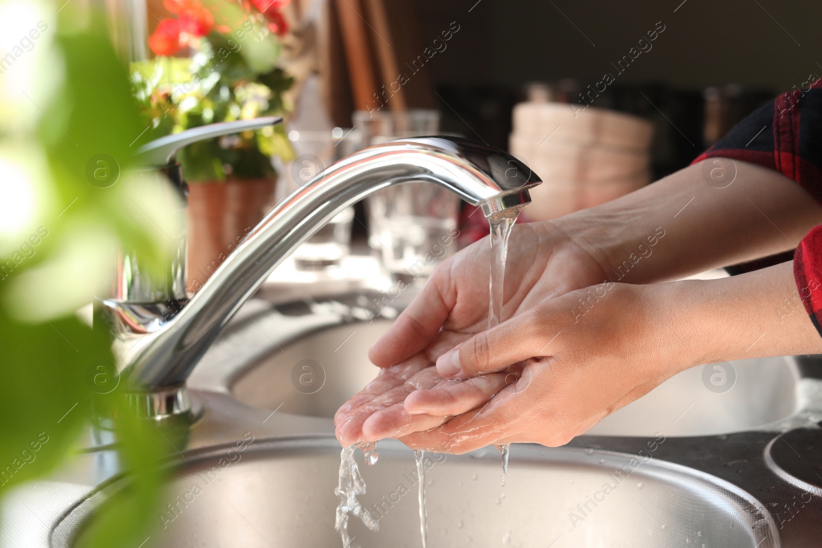 Photo of Woman washing hands in kitchen, closeup view