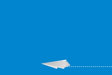 Image of Handmade white paper plane on blue background. Space for text