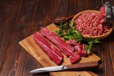 Photo of Manual meat grinder with beef, parsley and peppercorns on wooden table