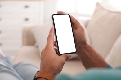 Photo of Man holding mobile phone with empty screen indoors, closeup