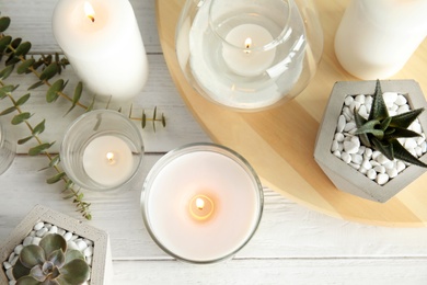 Flat lay composition with burning aromatic candles and plants on wooden table