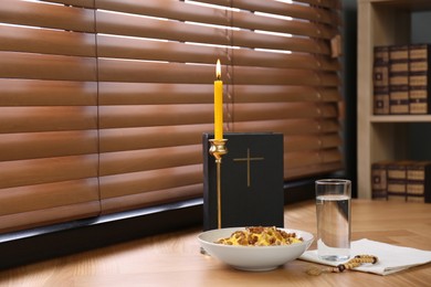 Photo of Great Lent dinner, Bible and candle near window indoors. Space for text