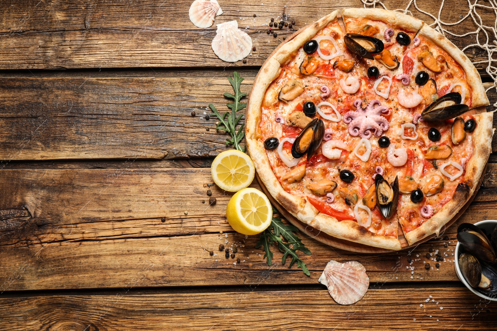 Photo of Delicious seafood pizza on wooden table, flat lay. Space for text