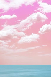 Image of Picturesque pink and coral sky with fluffy clouds over ocean