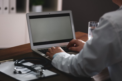 Professional doctor working on laptop in office, closeup