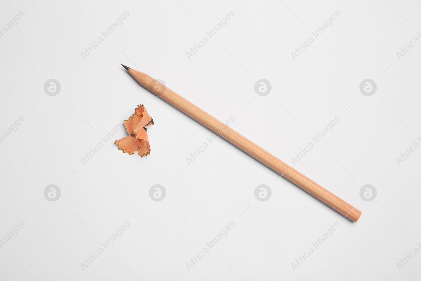 Photo of Graphite pencil and shavings on white background, flat lay