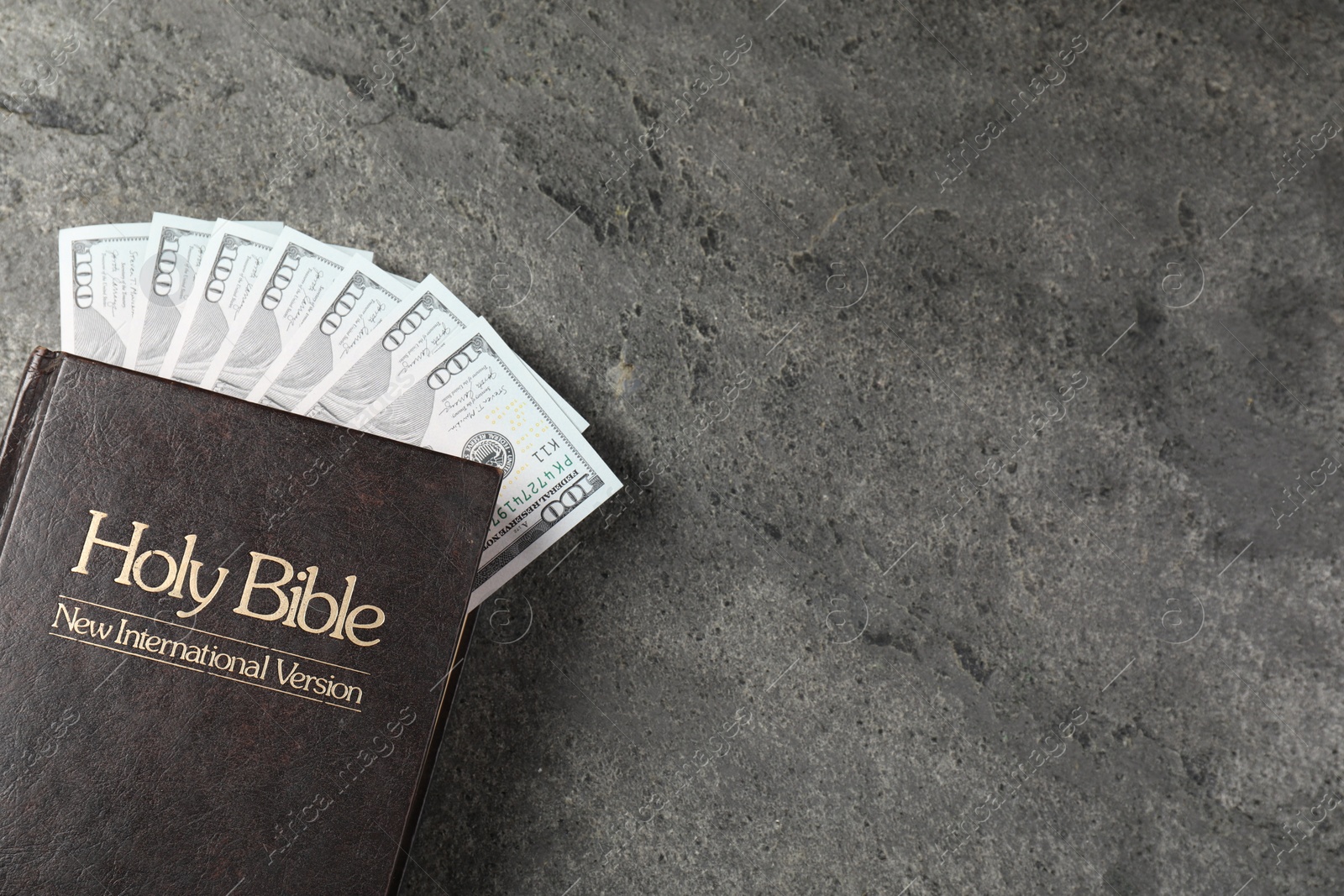 Photo of Holy Bible and money on grey table, top view. Space for text