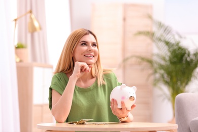 Photo of Woman with piggy bank and money at home