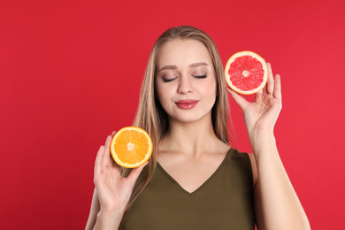 Photo of Young woman with cut orange and grapefruit on red background. Vitamin rich food