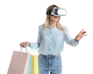 Young woman with shopping bags using virtual reality headset on white background