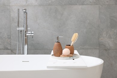 Photo of Different personal care products and accessories on bath tub in bathroom