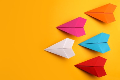 Photo of Handmade colorful paper planes on yellow background, flat lay. Space for text