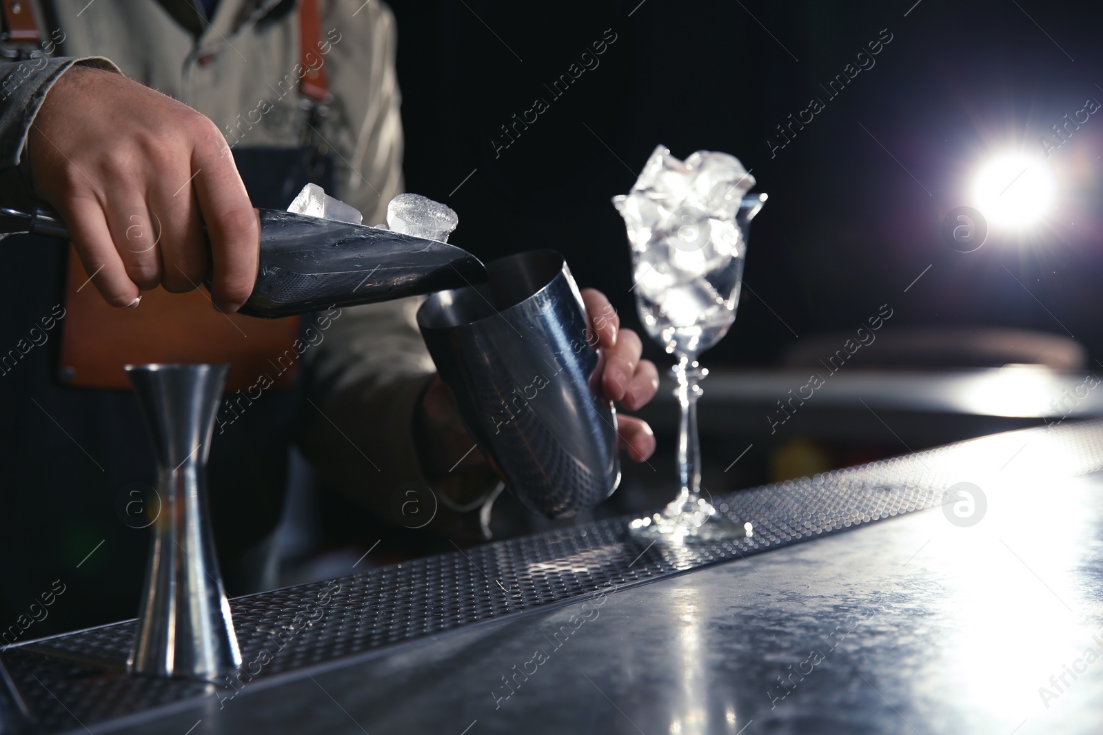 Photo of Barman adding ice into shaker at counter, closeup with space for text. Making martini cocktail