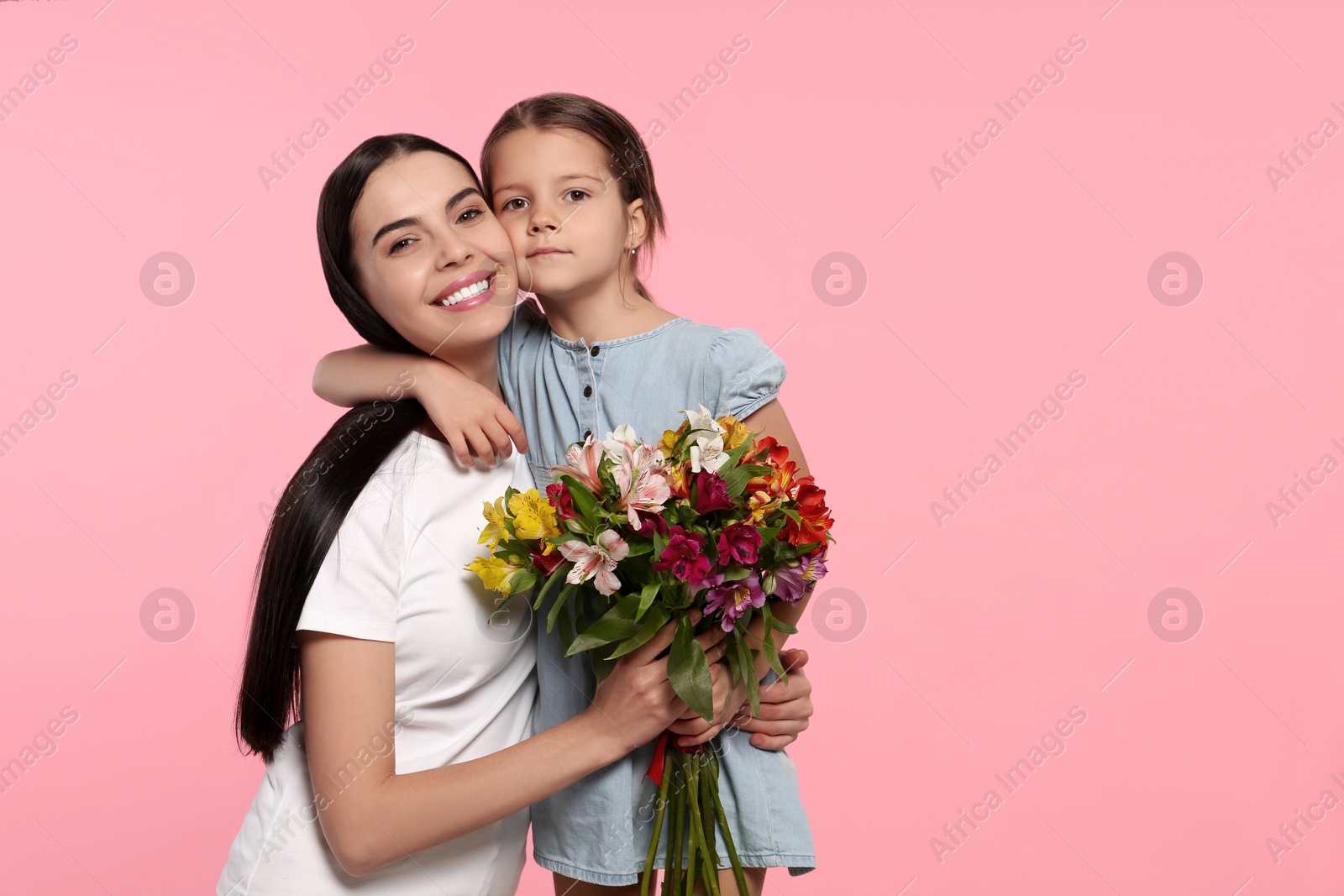 Photo of Happy woman with her daughter and bouquet of flowers on pink background, space for text. Mother's day celebration