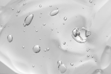 Photo of Transparent cleansing gel on light grey background, closeup. Cosmetic product