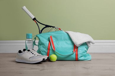 Photo of Bag with different sports equipment on wooden floor indoors