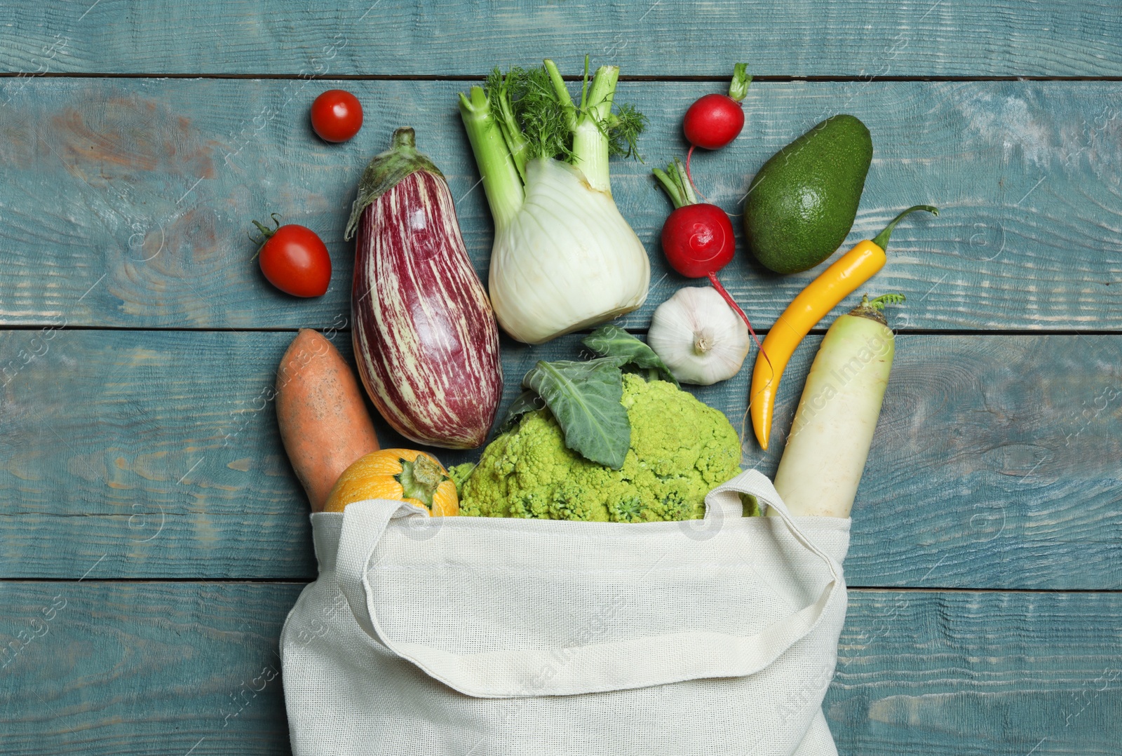 Photo of Overturned cloth bag with vegetables on wooden background, flat lay