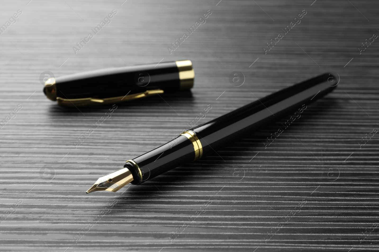 Photo of Stylish fountain pen on black wooden table, closeup